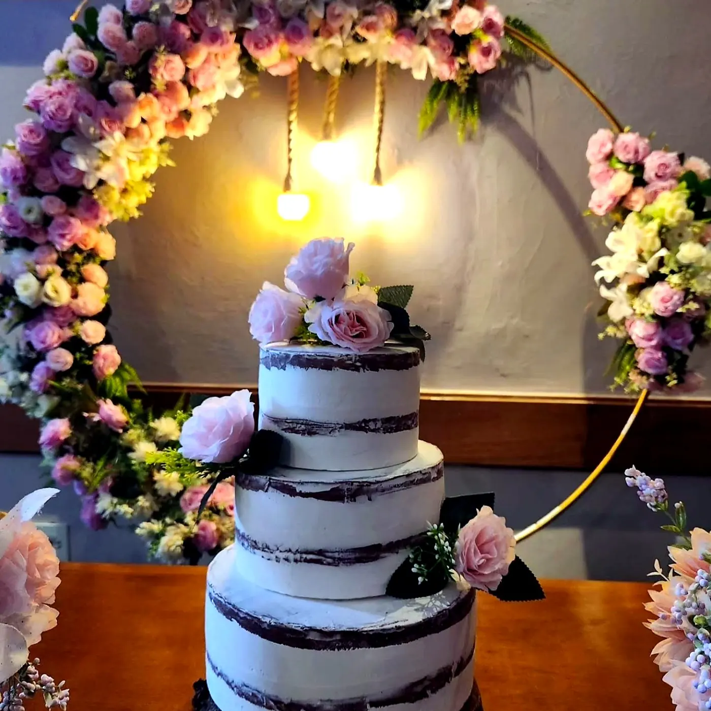 Bolo decorado com arco floral e iluminação quente